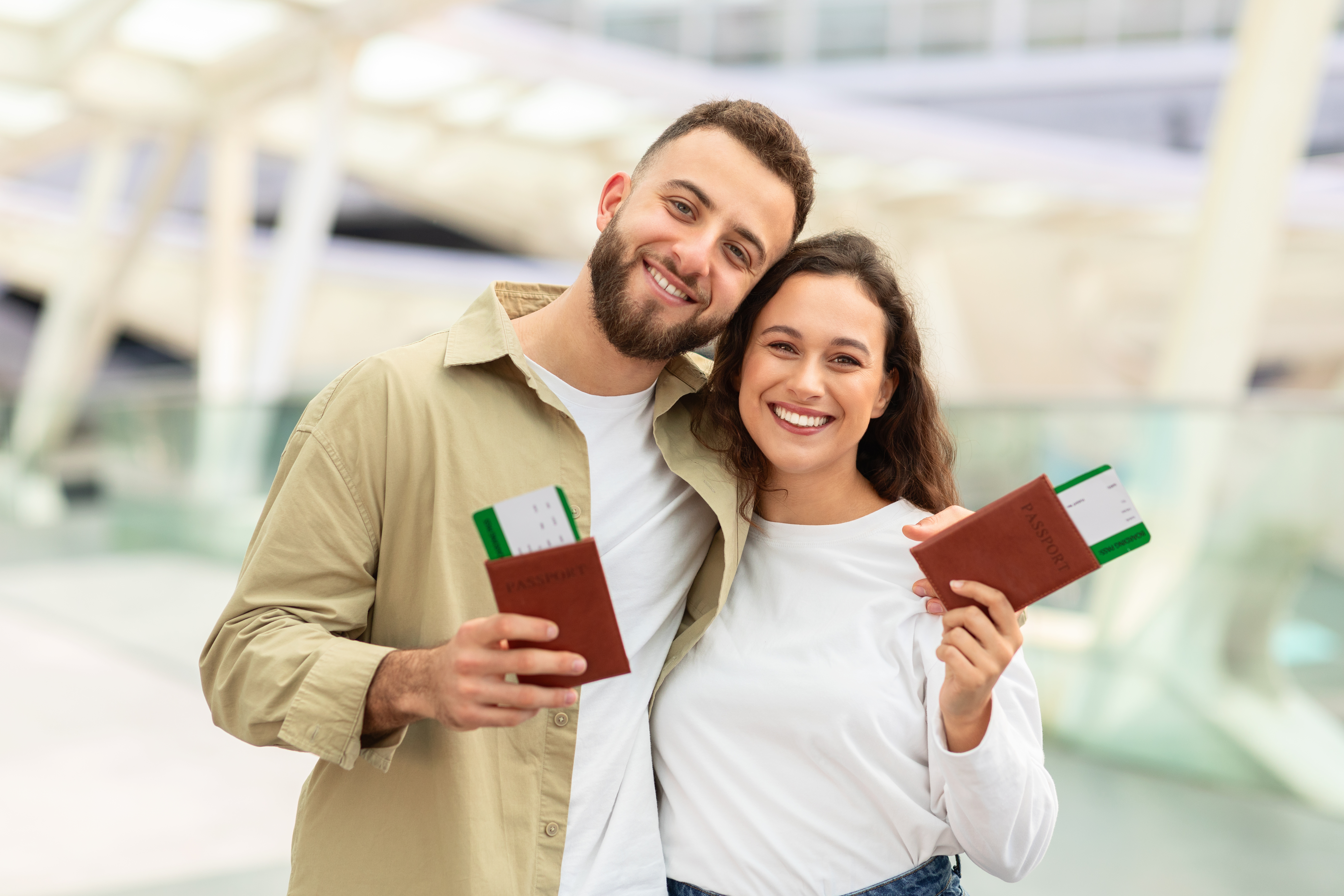 Excited couple holding passports at an airport terminal