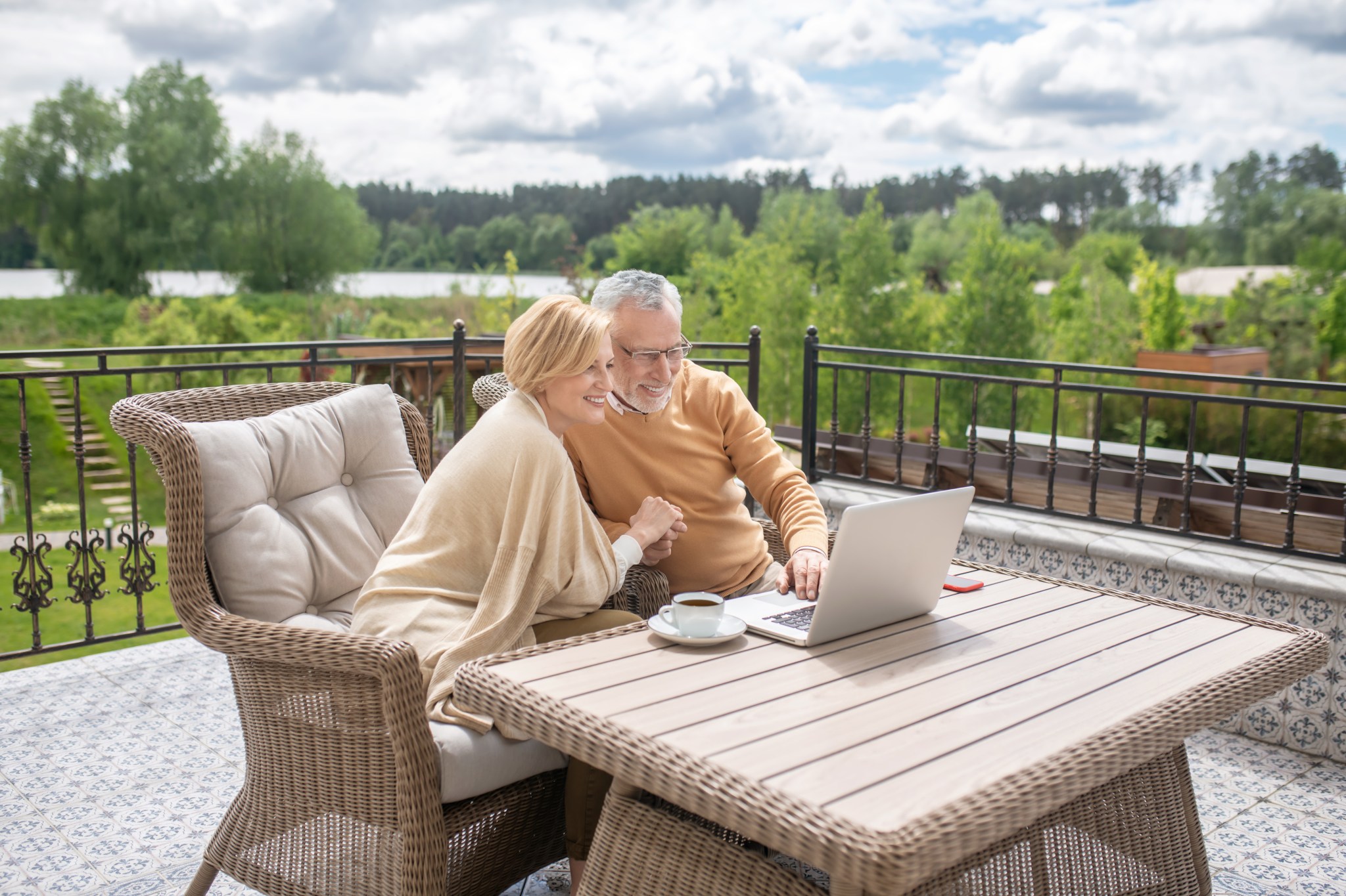 Happy couple using a laptop on a balcony
