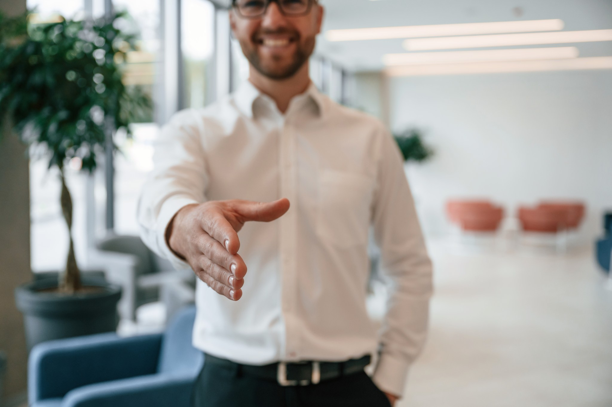 Professional offering a handshake in a modern office