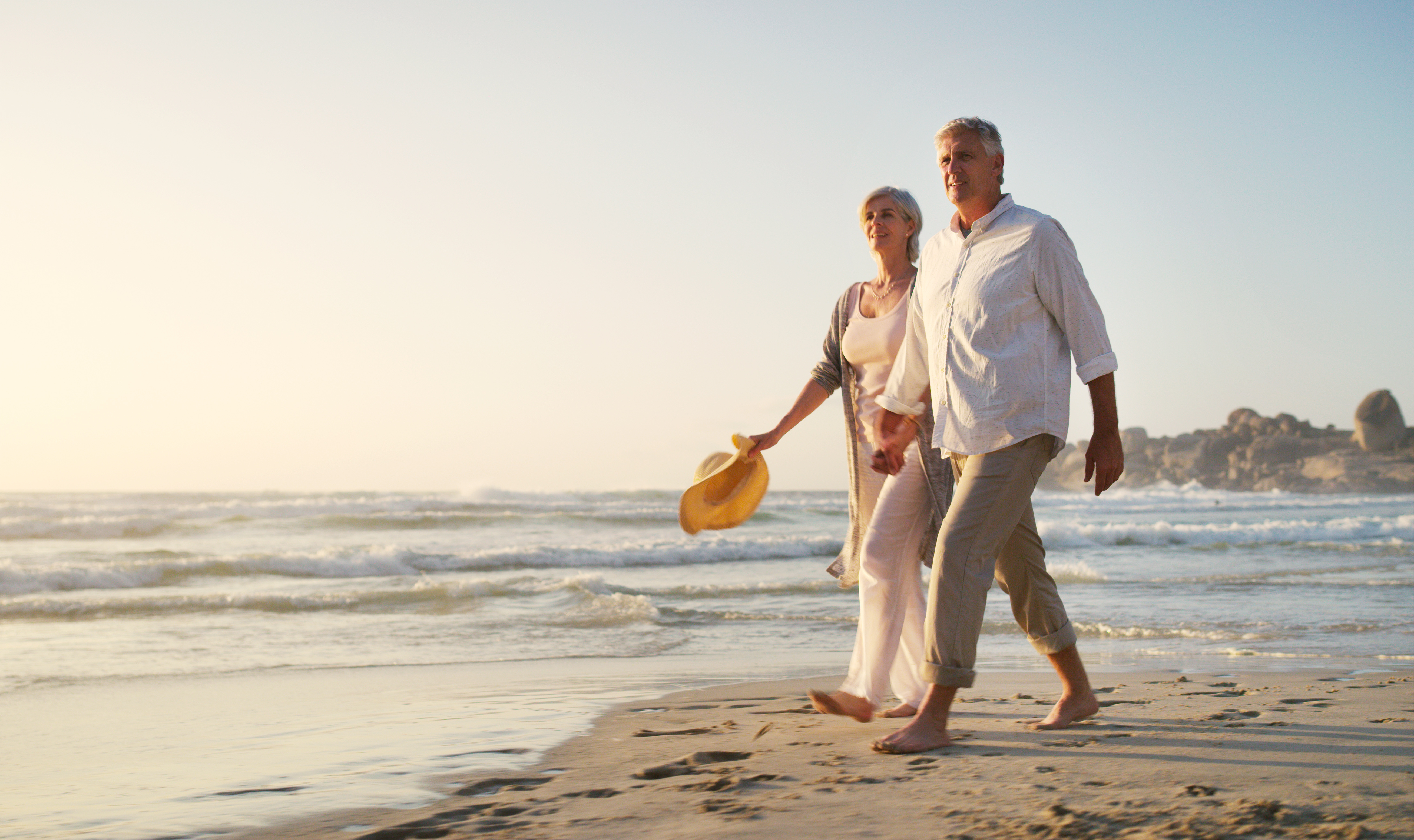 Senior couple walking hand in hand on a beach at sunset
