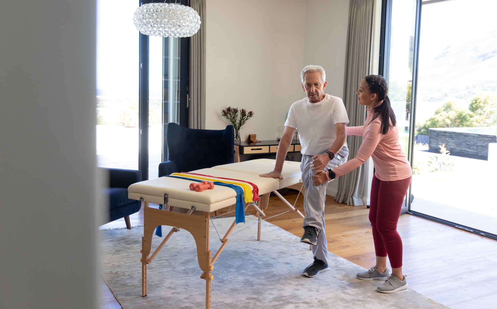 Senior man receiving assisted stretching therapy at home
