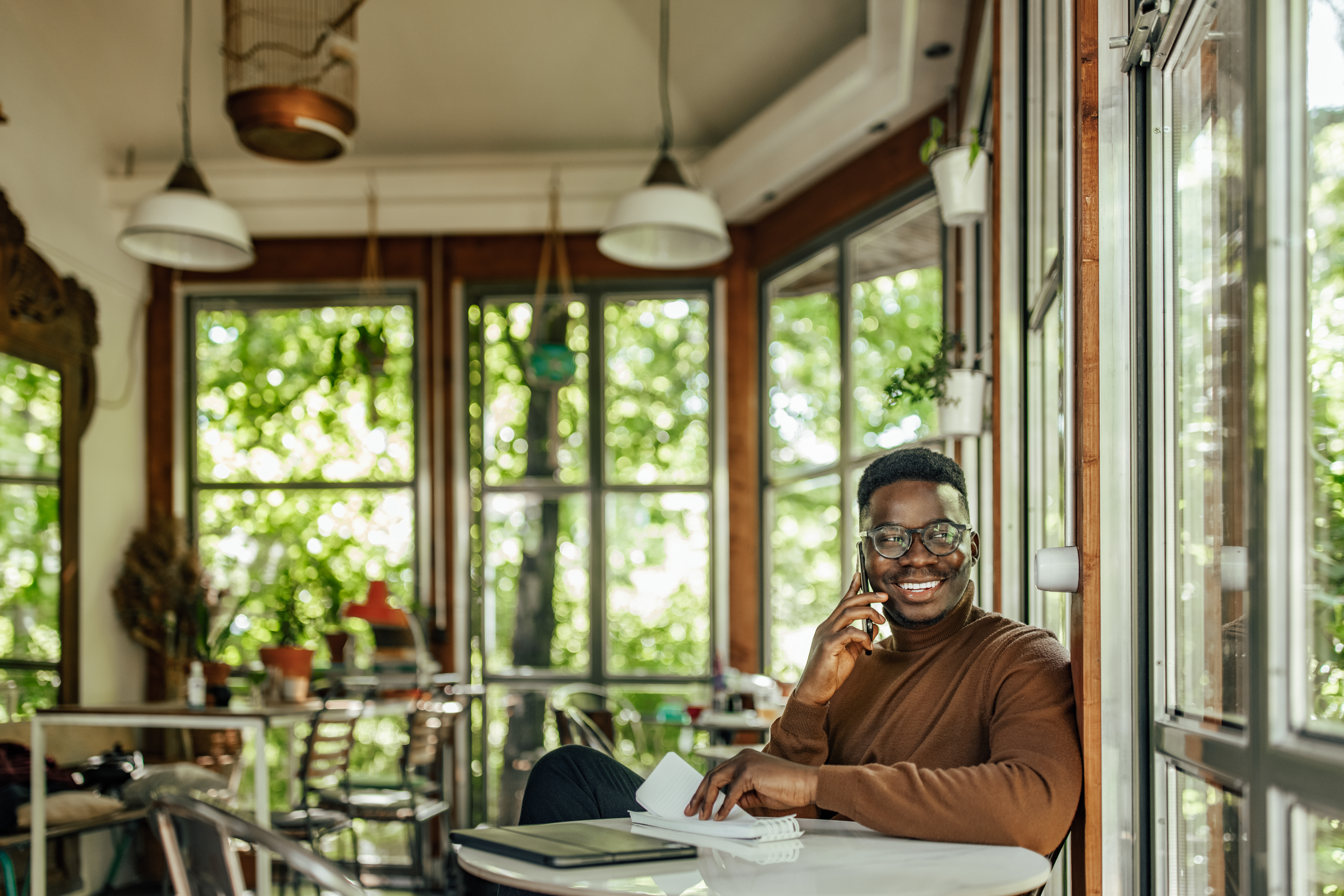 Business owner chatting on the phone in a sunny cafe