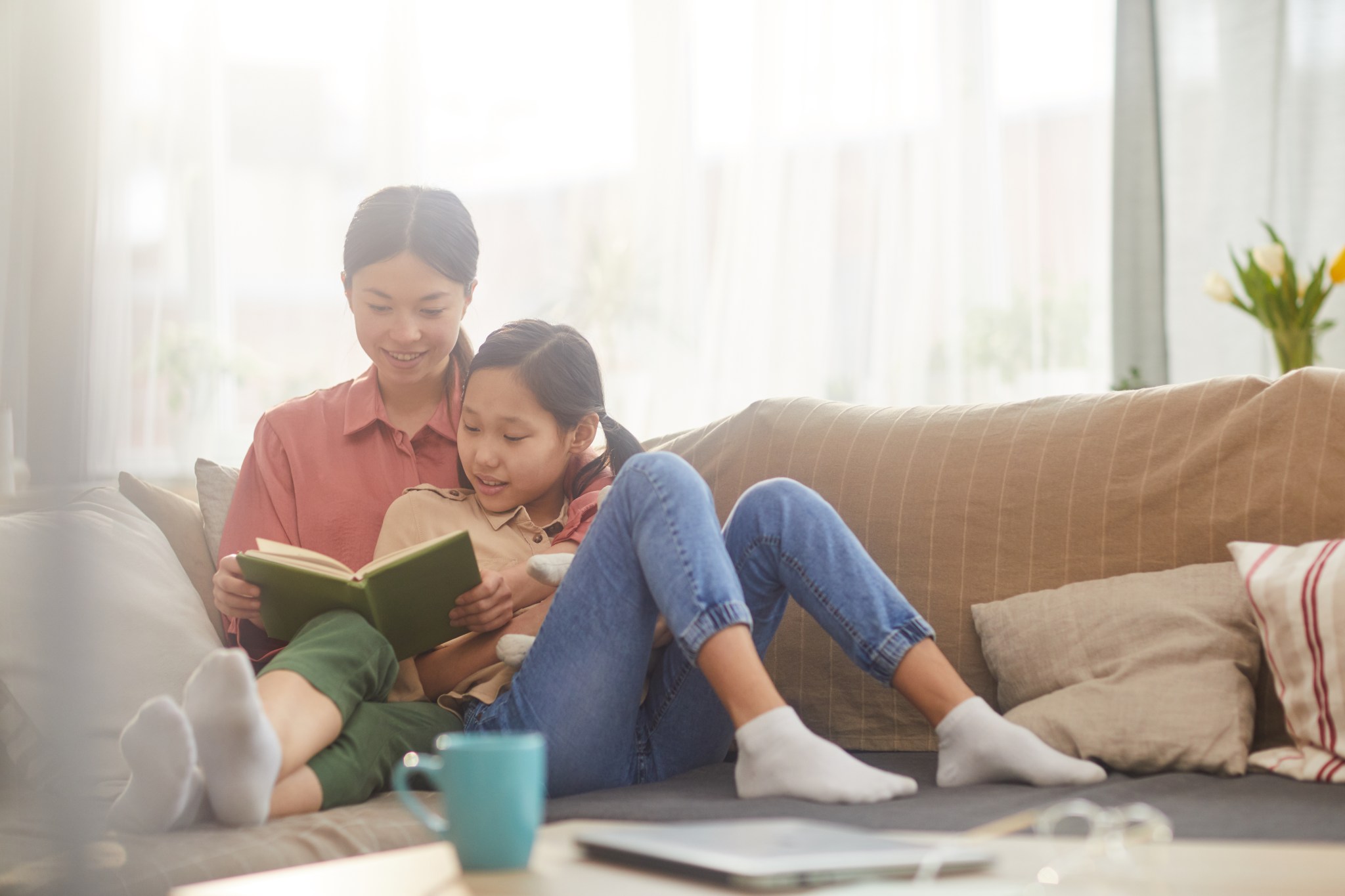 Teen and child reading together on a couch